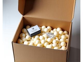 A shipping box made from recycled cardboard, casually opened to reveal art supplies nestled in biodegradable corn starch peanuts.